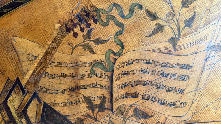 View of wooden commode top including sheet music detail at Ham House, London